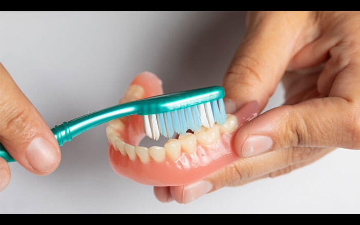 Cleaning dentures properly with a soft brush and soaking
